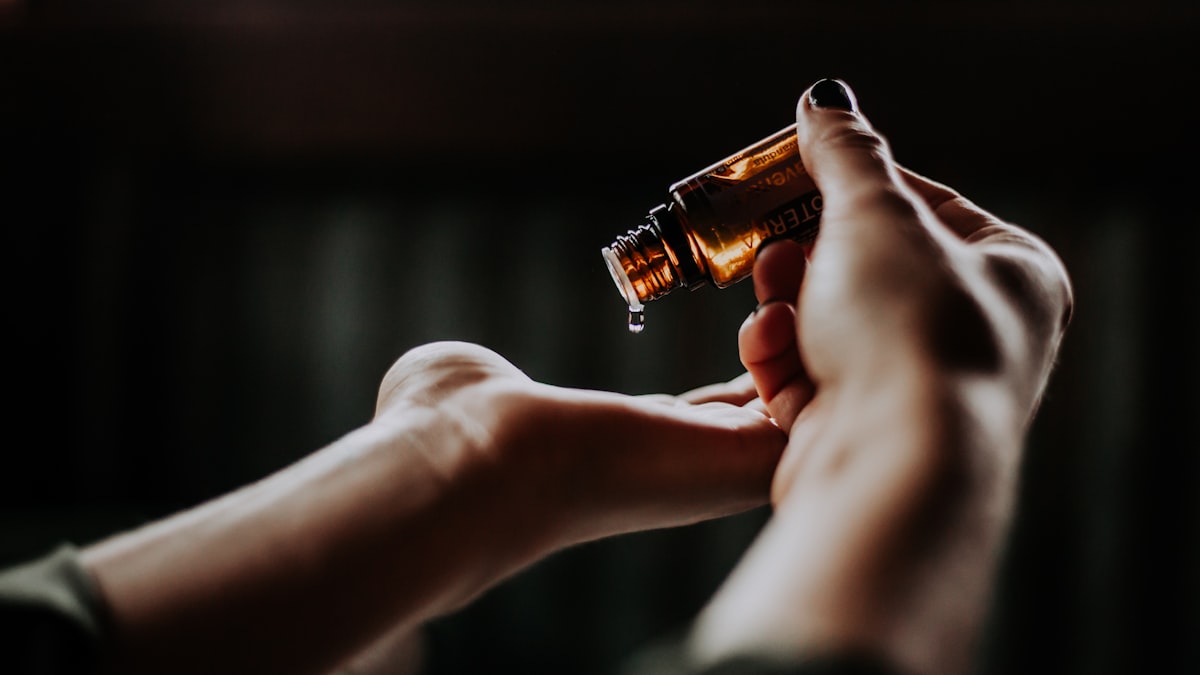 Small amber glass dropper bottle beside dried mushroom fragments on a cream surface